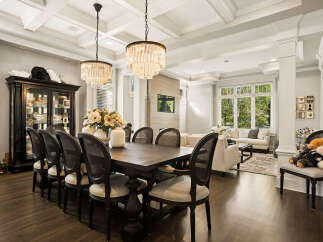 Experience elegant dining in this spacious room, featuring a dark wood dining table with upholstered chairs, illuminated by stunning crystal chandeliers.