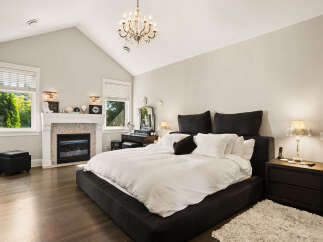 Experience luxury and comfort in this stunning bedroom, featuring a grand fireplace and a beautiful crystal chandelier.