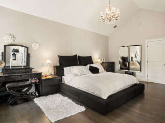 This luxurious bedroom features a spacious king-sized bed with crisp white linens and plush black pillows, complemented by elegant bedside tables and lamps.