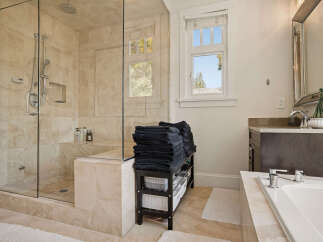 Experience luxury in this stunning bathroom featuring a spacious walk-in shower with elegant marble tiling and multiple shower heads.