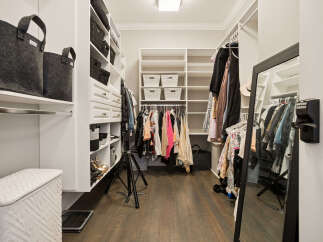Step into this spacious walk-in closet, meticulously organized with ample shelving and drawers for all your storage needs.