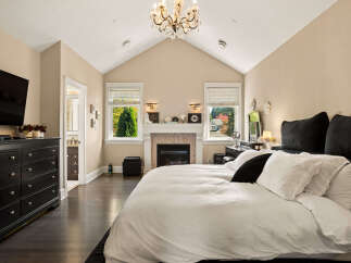 Experience luxury in this stunning master bedroom, featuring a cozy fireplace and a large TV for ultimate relaxation.