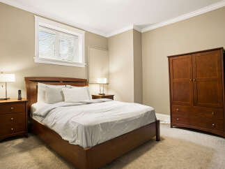 This inviting bedroom features a comfortable queen-size bed with crisp white linens and a stylish wooden headboard.