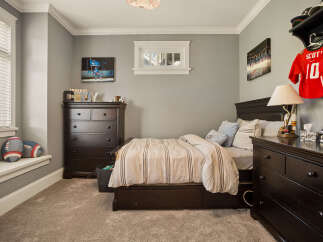 This charming bedroom is perfect for a young sports enthusiast, featuring a comfortable bed with striped bedding and a dark wood dresser.