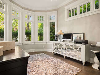 Bathed in natural light, this home office features a stunning bay window offering picturesque views of lush greenery.