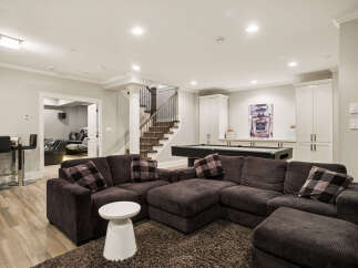 This finished basement offers a versatile entertainment space, featuring a large sectional sofa perfect for movie nights and a pool table for friendly competition.