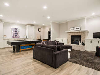 Experience ultimate entertainment in this stylish basement featuring a full-size pool table and a cozy living area with a modern fireplace.