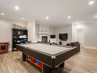 This spacious basement recreation room features a full-size pool table, perfect for entertaining guests or enjoying a night in.