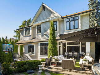 This stunning home boasts a spacious backyard perfect for entertaining, featuring a large patio with comfortable seating and a dining area under a generous umbrella.