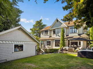 This stunning property boasts a spacious backyard perfect for entertaining, featuring a luxurious hot tub and a covered patio area with comfortable seating.