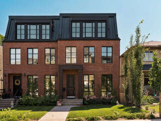 Discover modern urban living in this stunning red brick townhouse featuring a sleek black metal roof and expansive windows.