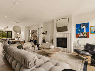 Experience modern living in this spacious open-concept home, featuring a cozy living area with a fireplace and a stylish tufted sofa.