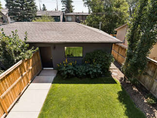 Discover this charming property featuring a well-maintained backyard with lush green grass and a wooden fence, perfect for outdoor enjoyment.