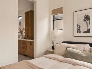 Experience modern living in this beautifully appointed bedroom, featuring a plush bed adorned with decorative pillows and a cozy throw.