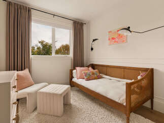 This charming bedroom features a cozy daybed with a woven rattan headboard, perfect for a child's room or guest space.