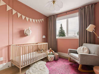 This charming nursery features a light wood crib adorned with stuffed animals, complemented by a plush white rug and a vibrant pink distressed rug.