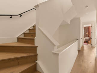 Experience modern living with this stunning staircase featuring warm oak treads and a sleek black handrail.