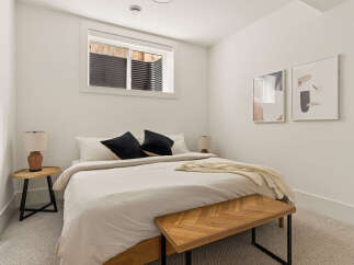 This cozy bedroom features a comfortable queen-size bed with plush black accent pillows and a soft, neutral-toned duvet.