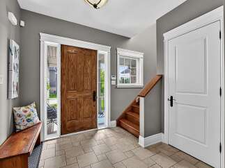Step into this welcoming entryway featuring a beautiful wooden front door with sidelights, perfect for natural light.