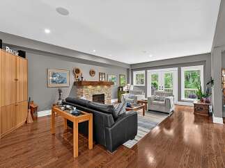 Step into this inviting living room featuring a cozy stone fireplace and a plush black leather sofa, perfect for relaxation.
