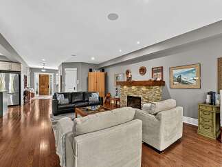 This spacious living area features a modern black leather sofa complemented by two plush, light-colored armchairs, creating a comfortable seating arrangement.