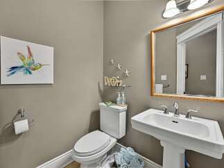 This charming powder room features a vibrant hummingbird artwork and a decorative 'DREAM' sign, adding a touch of personality.
