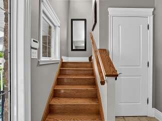 Ascend to the upper level via this beautifully crafted wooden staircase, featuring a warm oak finish and a sturdy handrail.