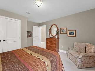 This charming bedroom features a cozy bed with a patterned comforter, complemented by a wooden dresser with an oval mirror.