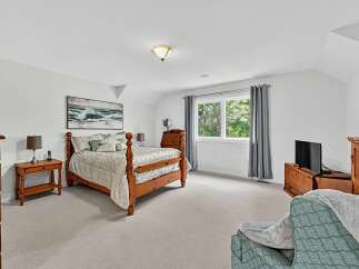 This charming bedroom features a cozy wooden bed with a patterned comforter, complemented by a matching nightstand with a lamp.