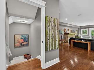 Step into a beautifully finished basement featuring a cozy living area with a stone fireplace and ample natural light from large windows and French doors.