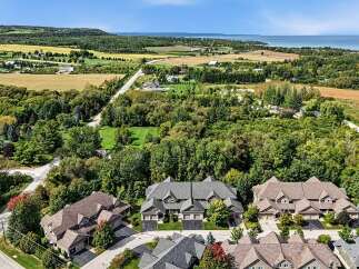 Discover this stunning aerial view of a modern residential community nestled amidst lush greenery and rolling hills.