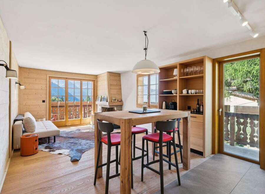Experience alpine living in this charming mountain retreat, featuring a cozy living area with a fireplace and stunning panoramic views from the balcony.