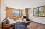 Experience mountain living in this charming living room featuring a cozy fireplace and stunning panoramic views from the balcony.