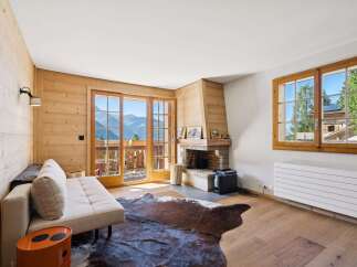 Experience mountain living in this charming living room featuring a cozy fireplace and stunning panoramic views from the balcony.
