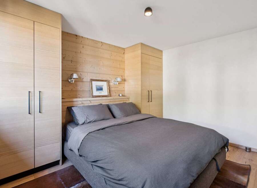 Experience cozy mountain living in this charming bedroom featuring warm wood paneling and ample built-in storage.