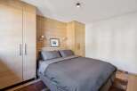 Experience cozy mountain living in this charming bedroom featuring warm wood paneling and ample built-in storage.