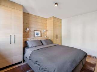 Experience cozy mountain living in this charming bedroom featuring warm wood paneling and ample built-in storage.