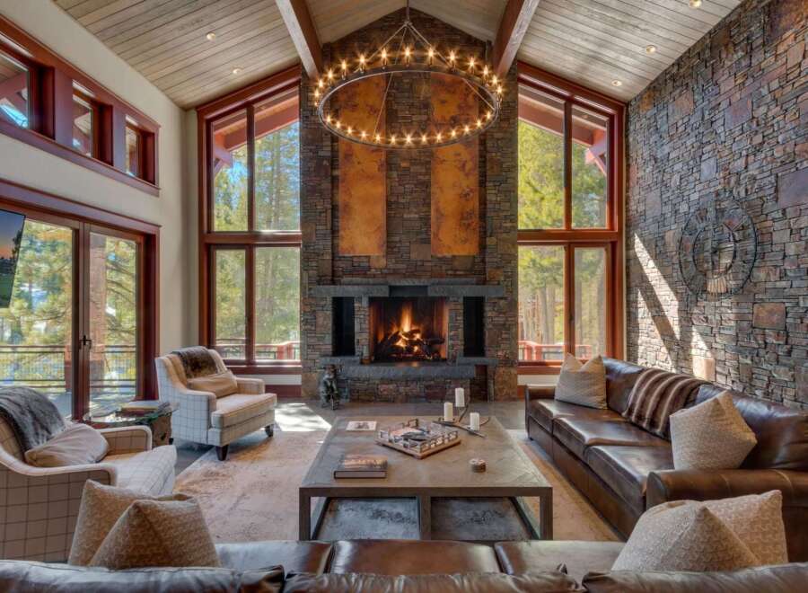Experience luxurious mountain living in this stunning great room, featuring a grand stone fireplace and soaring vaulted ceilings with exposed wood beams.