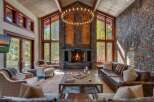 Experience luxurious mountain living in this stunning great room, featuring a grand stone fireplace and soaring vaulted ceilings with exposed wood beams.