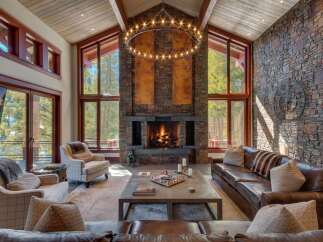 Experience luxurious mountain living in this stunning great room, featuring a grand stone fireplace and soaring vaulted ceilings with exposed wood beams.