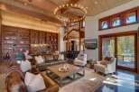 Experience luxurious mountain living in this stunning great room, featuring a grand circular chandelier and soaring wood-beamed ceilings.