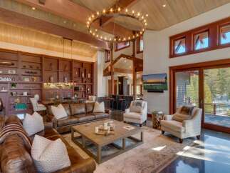 Experience luxurious mountain living in this stunning great room, featuring a grand circular chandelier and soaring wood-beamed ceilings.
