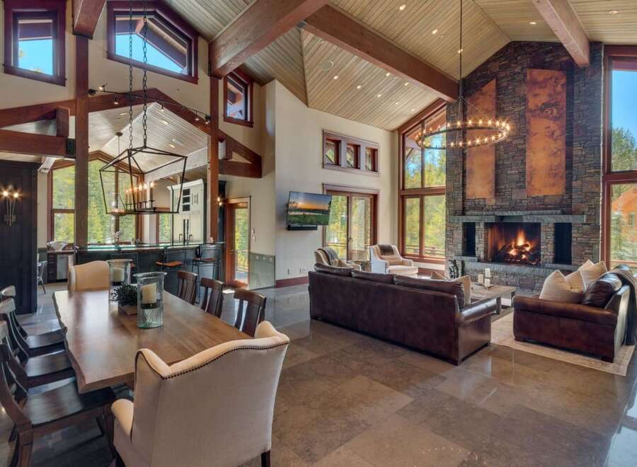 Experience luxurious mountain living in this stunning great room, featuring a soaring vaulted ceiling with exposed wooden beams and a magnificent floor-to-ceiling stone fireplace.