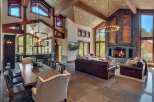 Experience luxurious mountain living in this stunning great room, featuring a soaring vaulted ceiling with exposed wooden beams and a magnificent floor-to-ceiling stone fireplace.