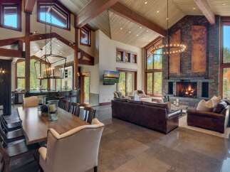 Experience luxurious mountain living in this stunning great room, featuring a soaring vaulted ceiling with exposed wooden beams and a magnificent floor-to-ceiling stone fireplace.