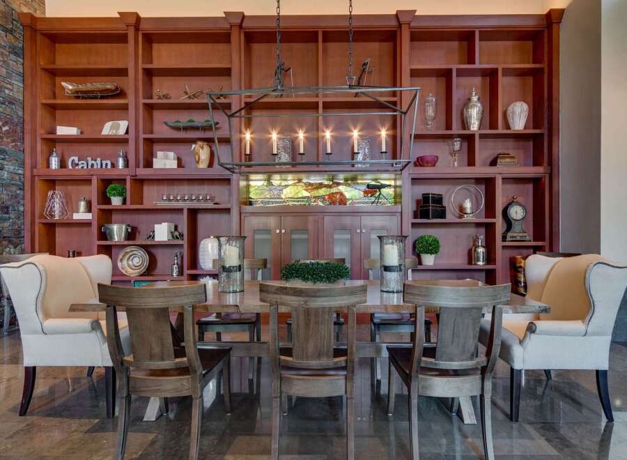 Experience elegant dining in this stunning room, featuring a grand wooden bookshelf filled with decorative items and a striking chandelier.