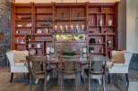 Experience elegant dining in this stunning room, featuring a grand wooden bookshelf filled with decorative items and a striking chandelier.