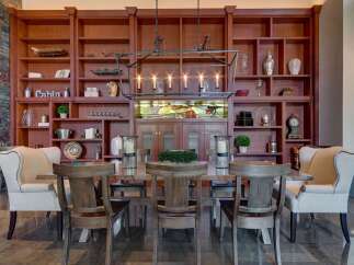 Experience elegant dining in this stunning room, featuring a grand wooden bookshelf filled with decorative items and a striking chandelier.