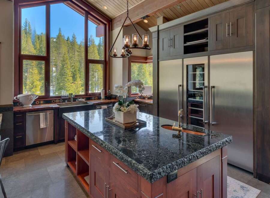 Experience luxury mountain living in this stunning kitchen, featuring a large granite island with a sink and ample seating.