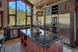 Experience luxury mountain living in this stunning kitchen, featuring a large granite island with a sink and ample seating.